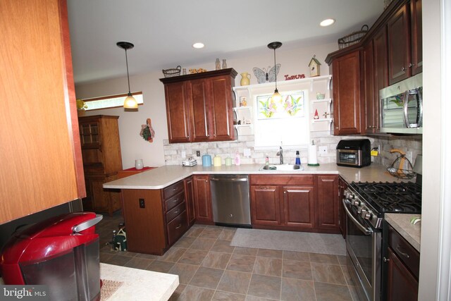 kitchen featuring backsplash, light countertops, appliances with stainless steel finishes, a peninsula, and a sink
