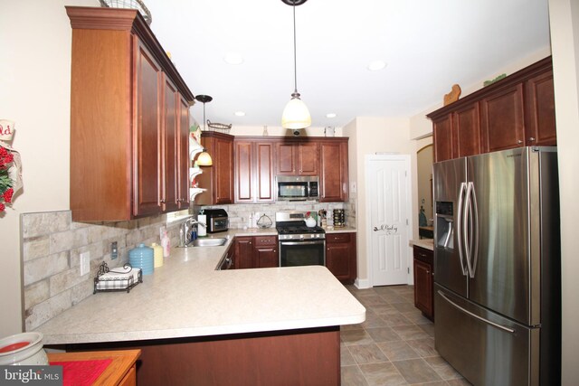 kitchen with a peninsula, a sink, light countertops, appliances with stainless steel finishes, and tasteful backsplash