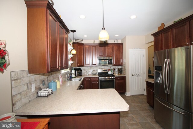 kitchen with a peninsula, a sink, stainless steel appliances, light countertops, and backsplash
