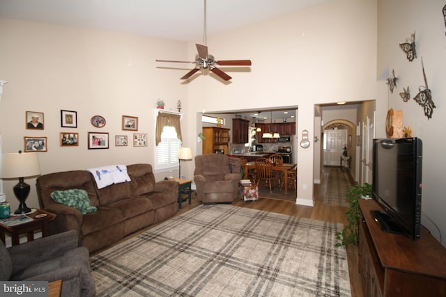 living room featuring high vaulted ceiling, ceiling fan, and wood-type flooring