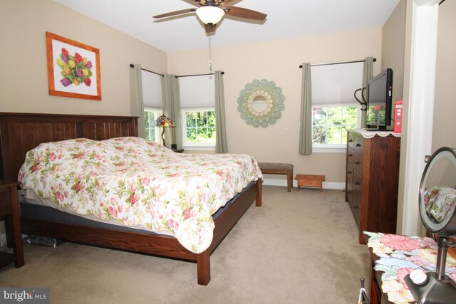 bedroom with ceiling fan, baseboards, and light carpet