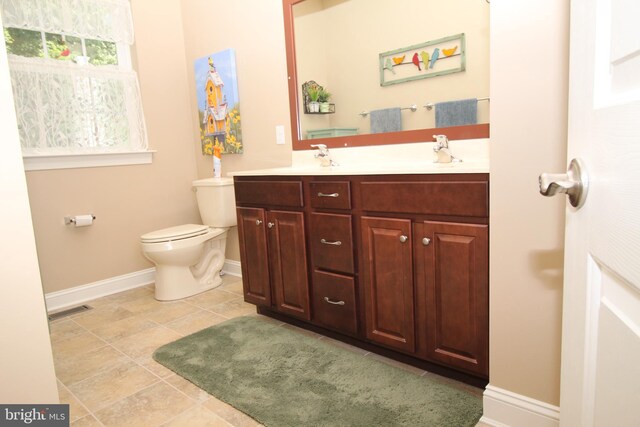bathroom featuring baseboards, visible vents, double vanity, tile patterned flooring, and toilet