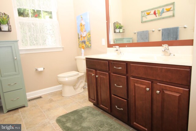 bathroom with visible vents, baseboards, toilet, double vanity, and a sink