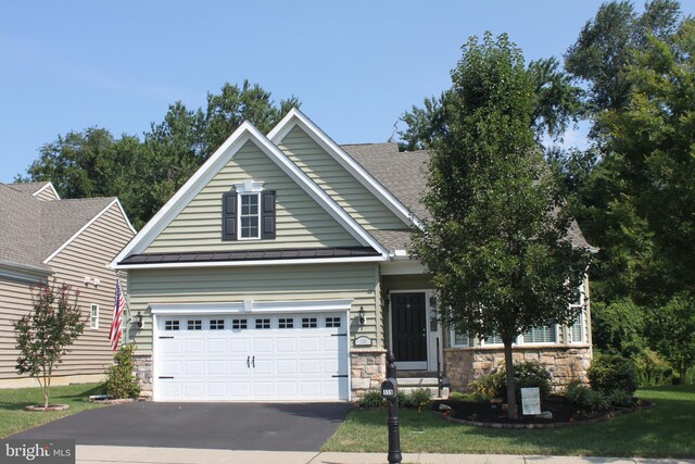 craftsman-style house with driveway, a standing seam roof, stone siding, roof with shingles, and a garage