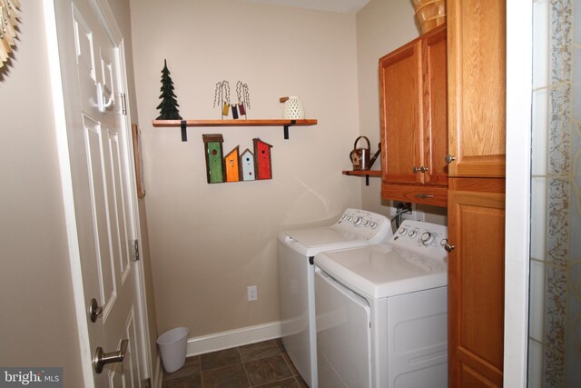 clothes washing area featuring cabinet space, washer and dryer, baseboards, and dark tile patterned flooring