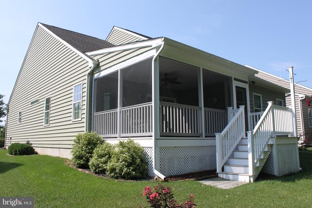 exterior space with a lawn, a shingled roof, stairs, and a sunroom