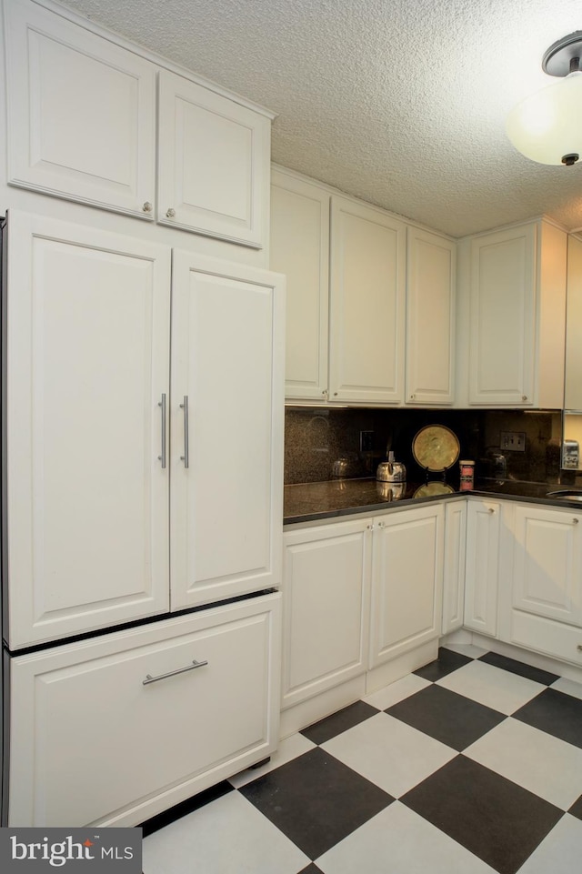 kitchen featuring white cabinetry, sink, backsplash, and a textured ceiling