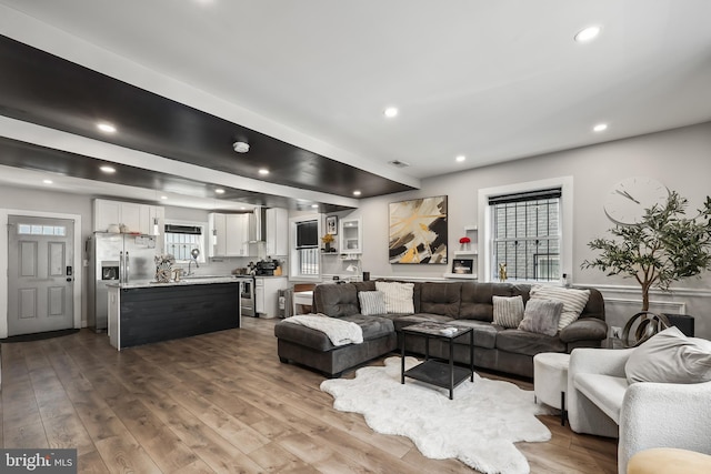 living room with light wood-type flooring, sink, and plenty of natural light