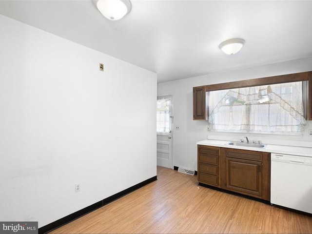 kitchen featuring white dishwasher, dark brown cabinets, light hardwood / wood-style floors, and sink