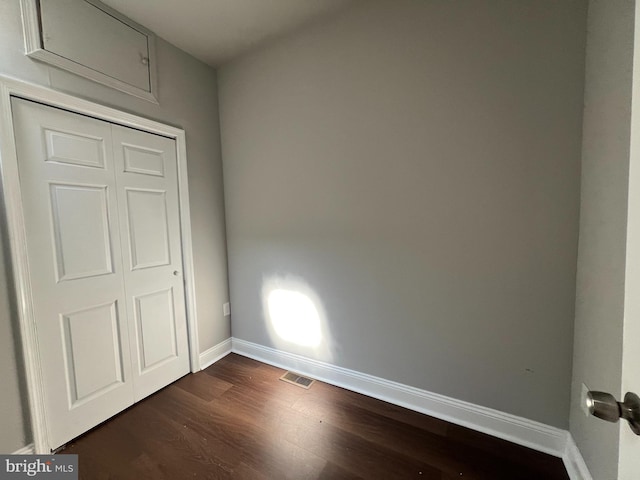 unfurnished bedroom with a closet and dark wood-type flooring