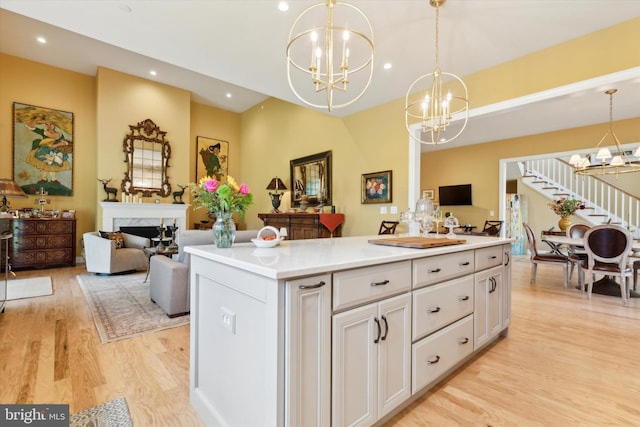 kitchen featuring a premium fireplace, pendant lighting, light wood-type flooring, and white cabinets