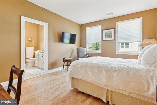 bedroom featuring ensuite bathroom and light wood-type flooring