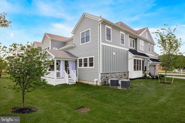 back of house featuring central air condition unit and a lawn