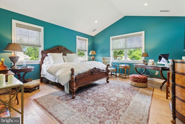 bedroom featuring multiple windows, light wood-type flooring, and vaulted ceiling