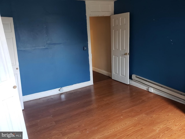 unfurnished room with a baseboard radiator and hardwood / wood-style floors