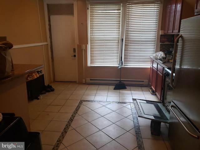 kitchen with plenty of natural light, light tile patterned floors, a baseboard heating unit, and refrigerator