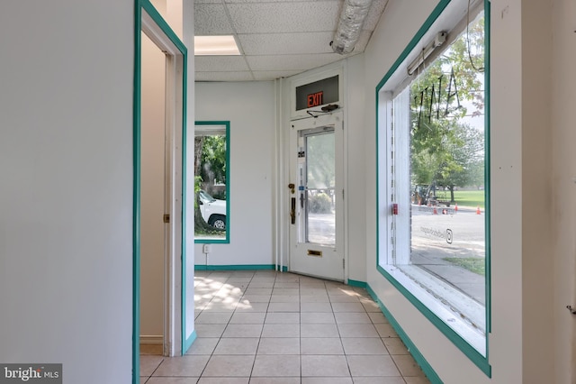 doorway to outside featuring a paneled ceiling, a healthy amount of sunlight, and light tile patterned floors