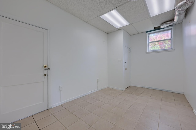 unfurnished room with light tile patterned floors and a drop ceiling