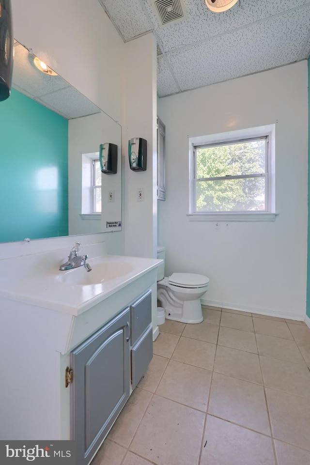 bathroom featuring a drop ceiling, toilet, vanity, and tile patterned floors