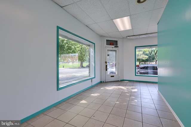 unfurnished room with a drop ceiling and light tile patterned flooring