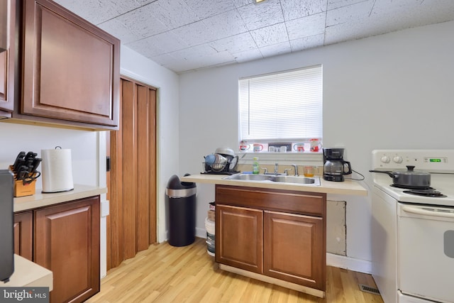 kitchen featuring sink, light wood-type flooring, and electric range