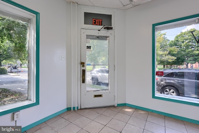 doorway to outside with light tile patterned flooring and a drop ceiling