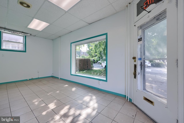 tiled empty room featuring a paneled ceiling