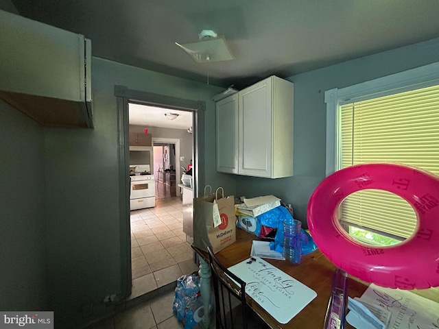 interior space with white cabinets, light tile patterned floors, and white gas range