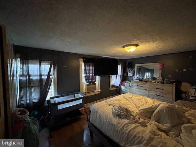 bedroom with dark wood-type flooring, a textured ceiling, and cooling unit