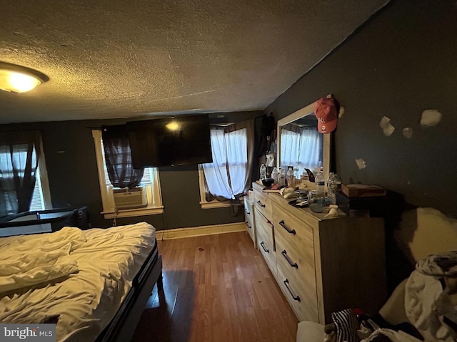 bedroom featuring cooling unit, dark hardwood / wood-style flooring, and a textured ceiling