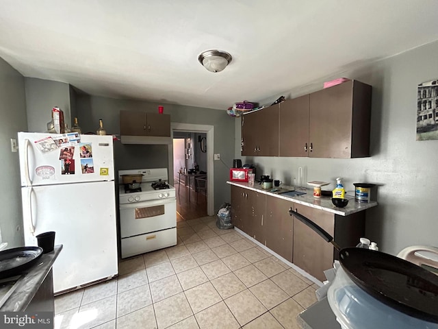 kitchen with light tile patterned floors, dark brown cabinets, and white appliances