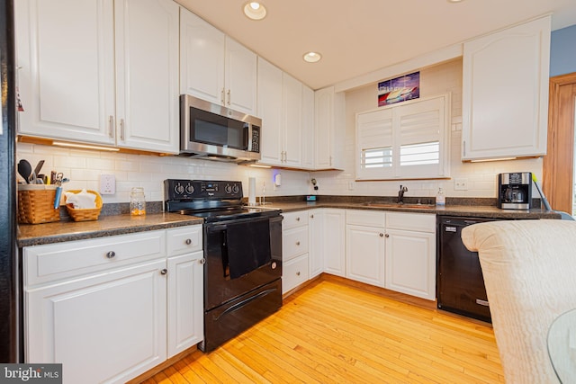 kitchen featuring white cabinetry, backsplash, light wood-type flooring, black appliances, and sink