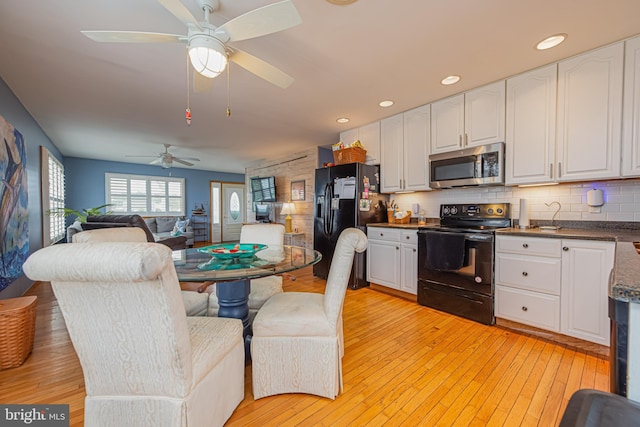 kitchen featuring white cabinetry, decorative backsplash, light hardwood / wood-style flooring, and black appliances