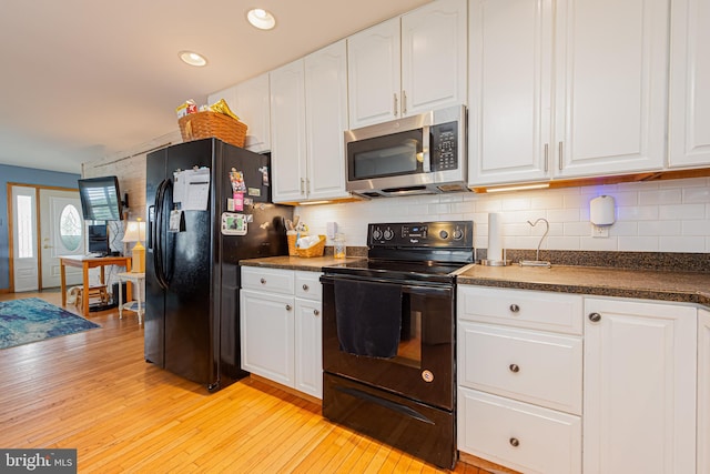 kitchen with decorative backsplash, white cabinets, black appliances, and light wood-type flooring