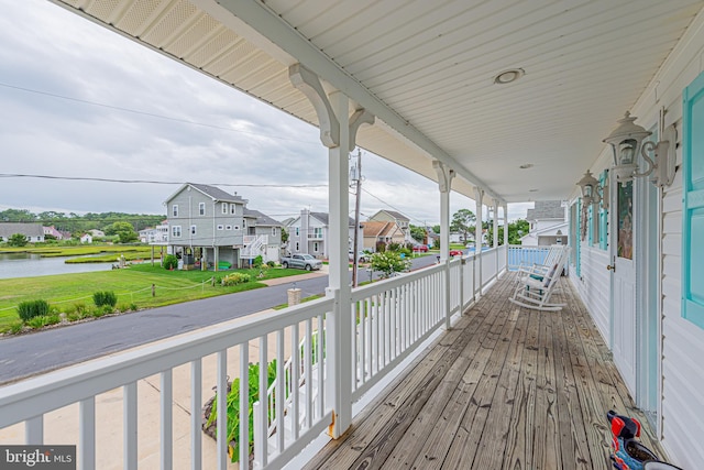 deck featuring covered porch and a water view