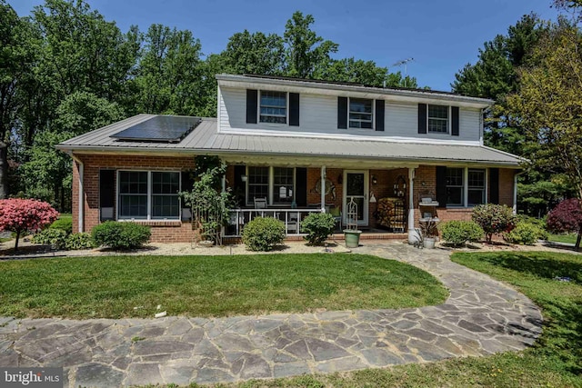 view of front of property featuring a front lawn, a porch, and solar panels