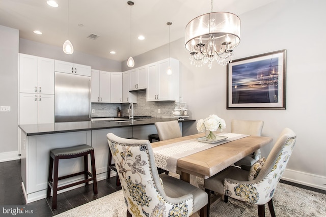 dining room with sink, dark hardwood / wood-style flooring, and a chandelier