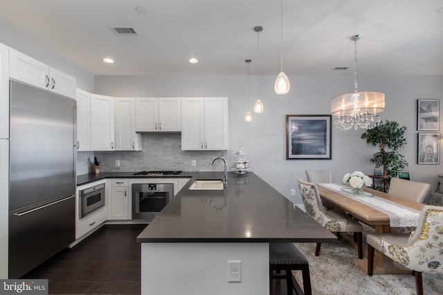 kitchen featuring backsplash, sink, hanging light fixtures, appliances with stainless steel finishes, and white cabinets