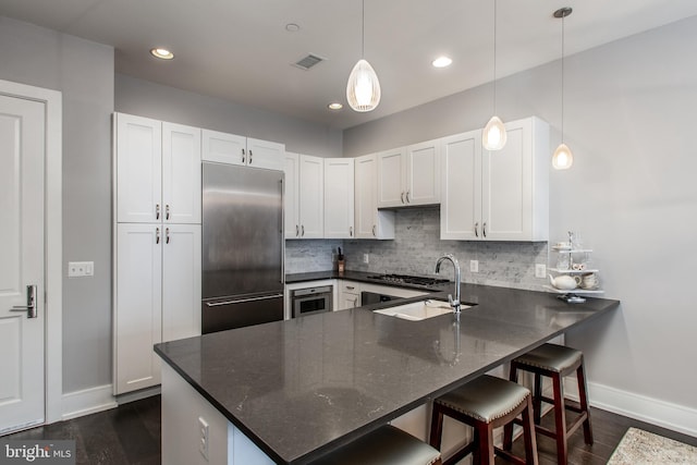 kitchen with white cabinetry, a kitchen bar, stainless steel built in fridge, pendant lighting, and sink