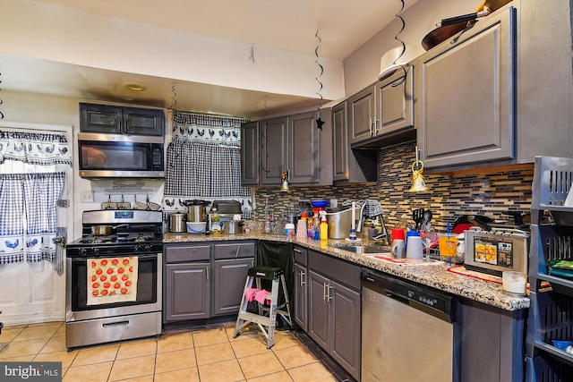 kitchen with appliances with stainless steel finishes, tasteful backsplash, sink, light tile patterned floors, and light stone countertops