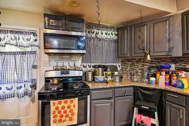 kitchen with dark brown cabinetry, tasteful backsplash, light stone countertops, and stainless steel appliances