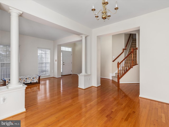 foyer with hardwood / wood-style floors, a chandelier, and ornate columns