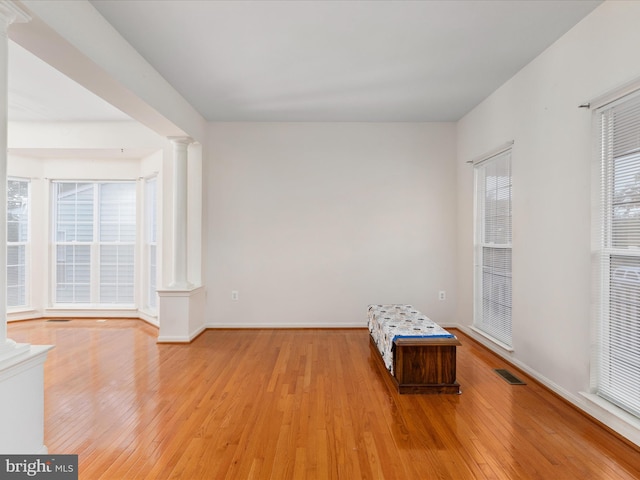 unfurnished room with decorative columns and light wood-type flooring