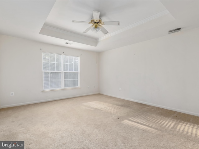 carpeted empty room featuring a tray ceiling, ornamental molding, and ceiling fan