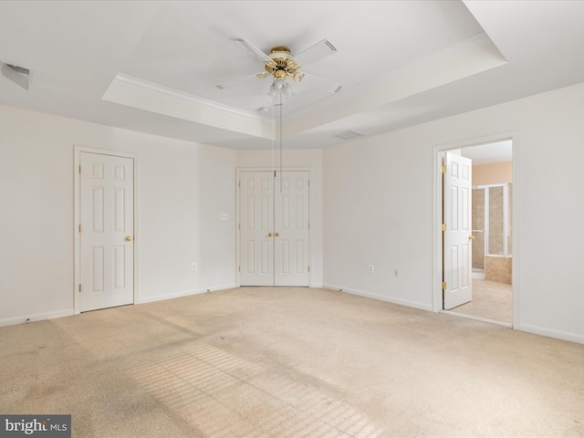 unfurnished room featuring a raised ceiling, crown molding, and light colored carpet