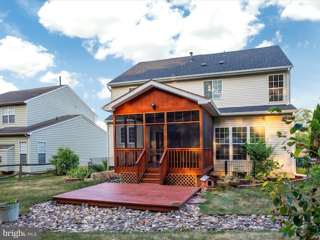 rear view of property featuring a yard, a sunroom, and a deck