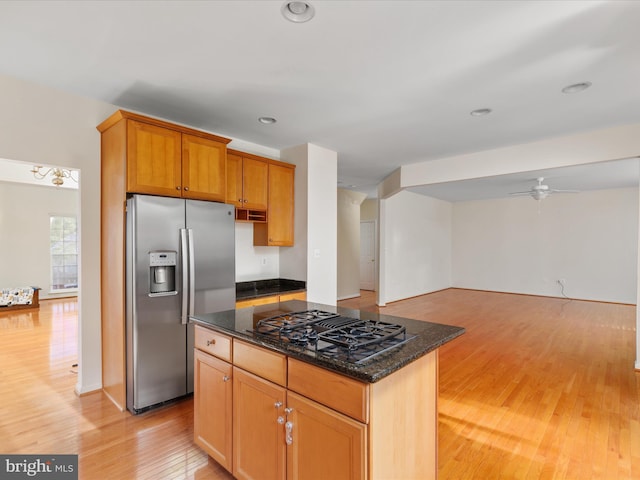 kitchen featuring stainless steel refrigerator with ice dispenser, dark stone countertops, a kitchen island, black gas cooktop, and light hardwood / wood-style floors