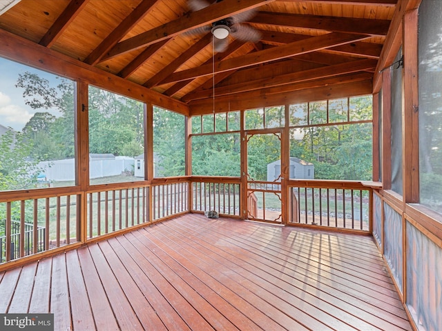 unfurnished sunroom with a wealth of natural light, lofted ceiling with beams, wooden ceiling, and ceiling fan