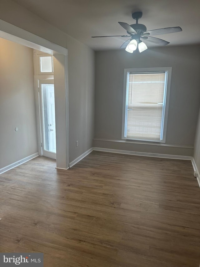 unfurnished room with ceiling fan, dark wood-type flooring, and a healthy amount of sunlight