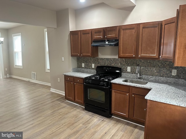 kitchen featuring light wood-type flooring, gas stove, light stone counters, and sink